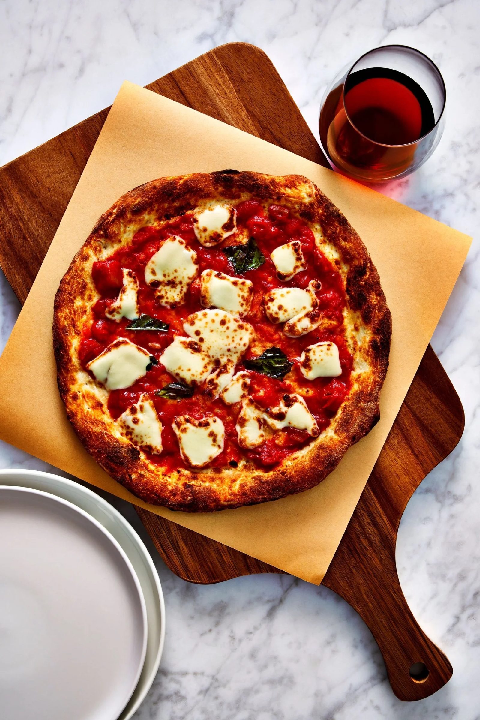 Personal pan pizza on a wooden board with a glass of wine