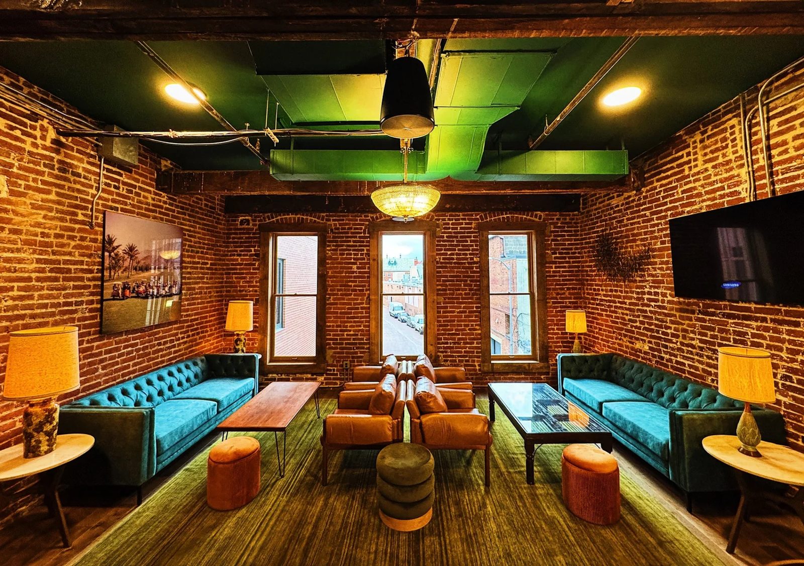 Private lounge with teal couches, exposed brick and warm lighting